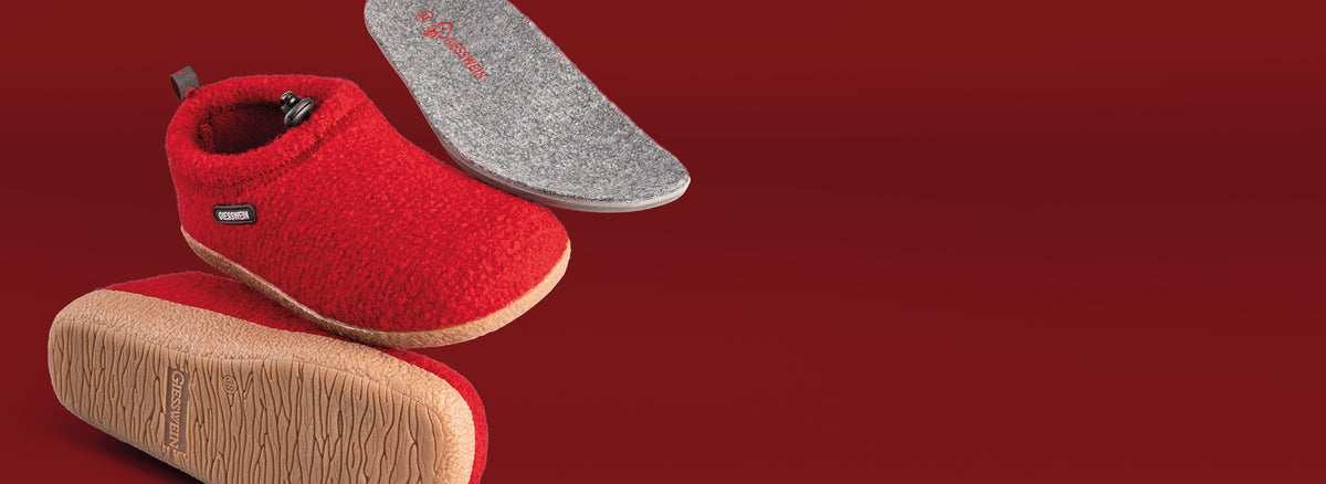 Red Giesswein wool slippers shown from multiple angles including sole, insole, and side views against a red background, displaying the textured outsole and gray branded insole.