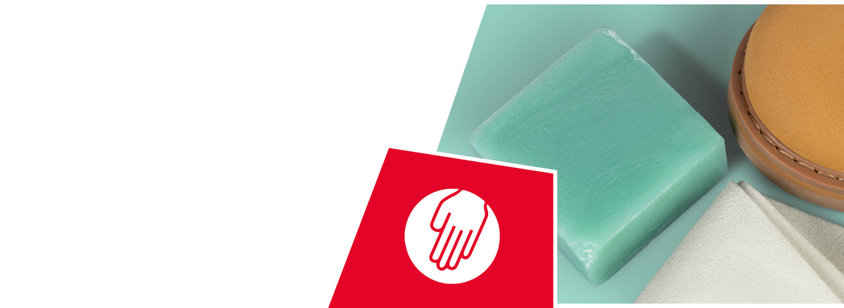 Green soap bar, beige shoe sole, and white towel arranged together. A red icon shows a white hand symbol, indicating hand-washable or care properties.