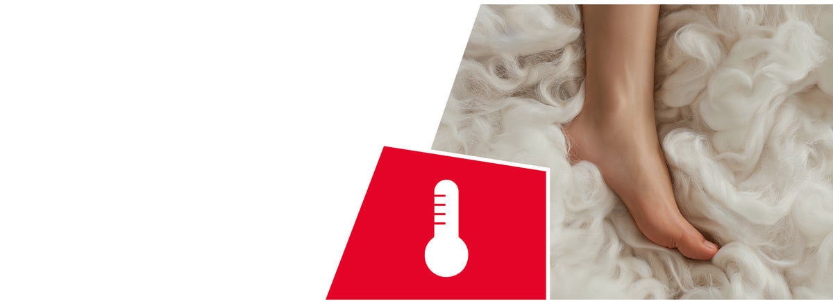 A person's foot surrounded by soft, fluffy white wool fibers. A red icon shows a white thermometer symbol, indicating temperature regulation properties.