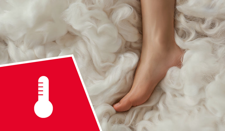A person's foot surrounded by soft, fluffy white wool fibers. A red icon shows a white thermometer symbol, indicating temperature regulation properties.
